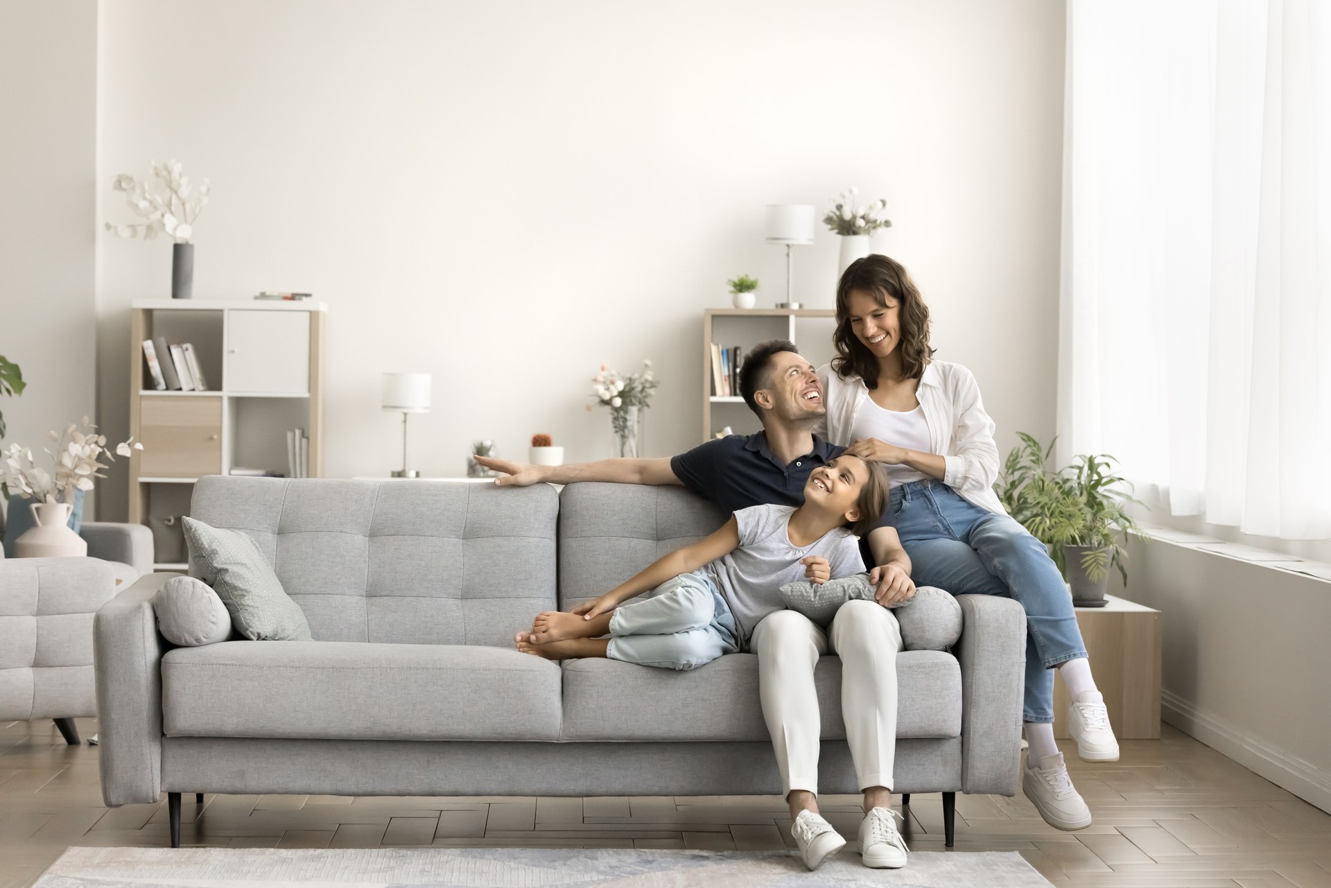 Happy parents and little daughter kid relaxing on sofa