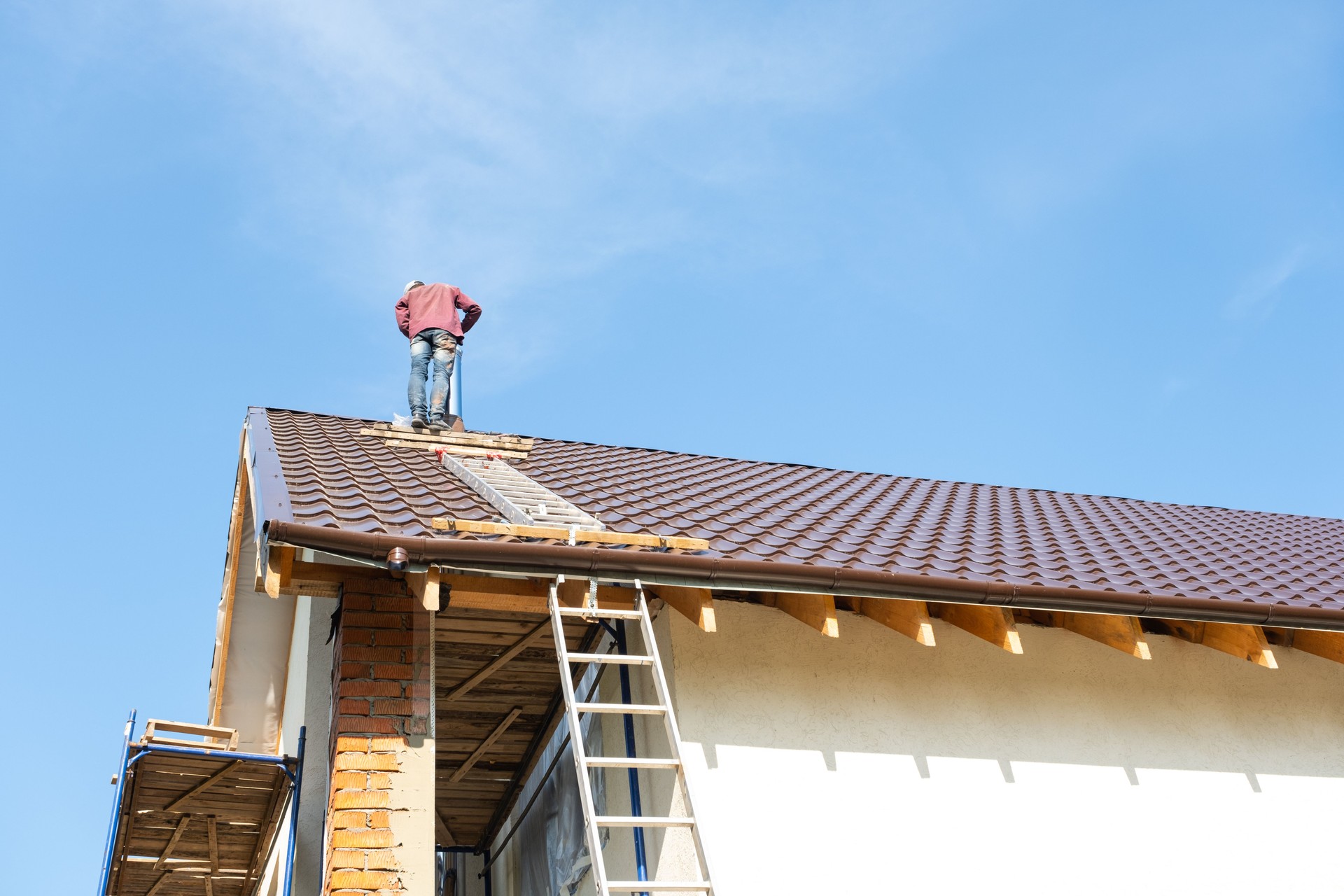 The master for the installation of ventilation pipes and the installation of the chimney of the furnace works on the roof of the house